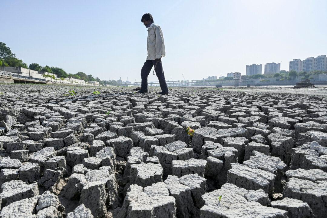 TOPSHOT - A man walks on the dry riverbed of the Sabarmati River in Ahmedabad on May 8, 2026. (Photo by Shammi MEHRA / AFP via Getty Images)