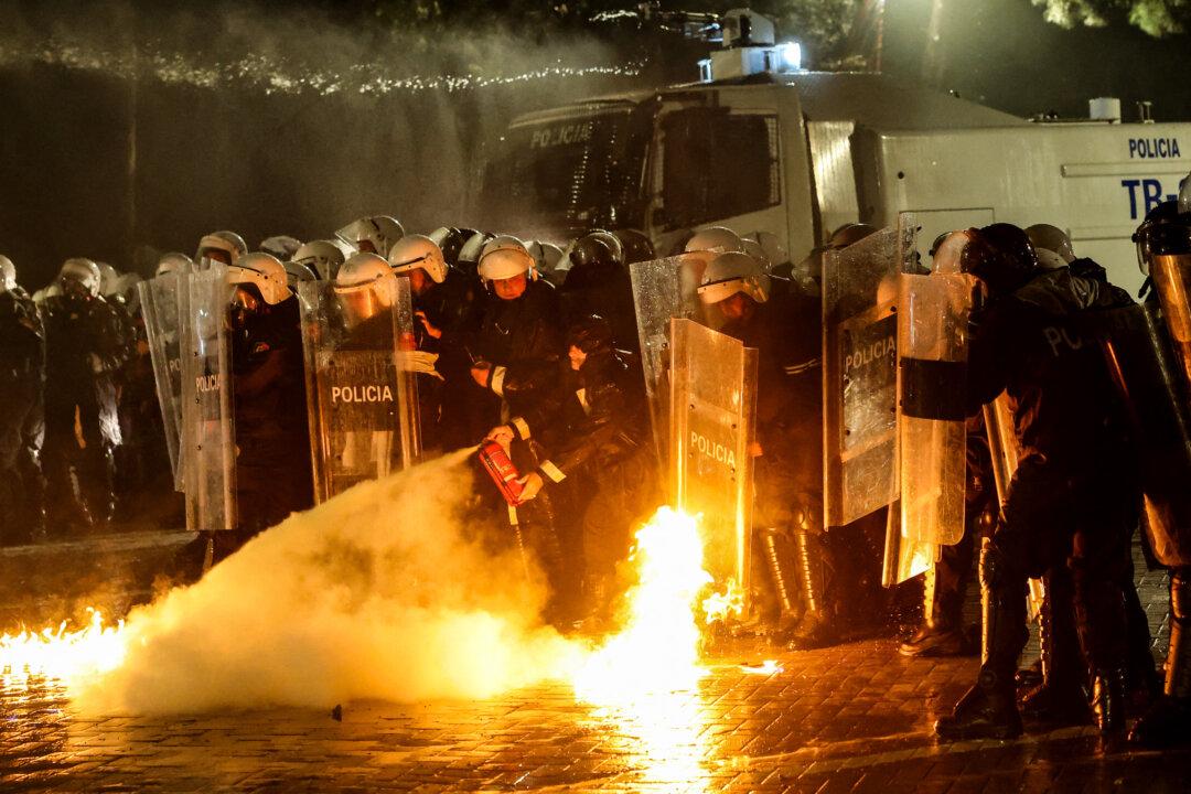 Albanian riot police officers use a fire extinguisher to put out a fire after being targeted with Molotov cocktails during an anti-government protest in Tirana on May 8, 2026. (Photo by Adnan Beci / AFP via Getty Images)