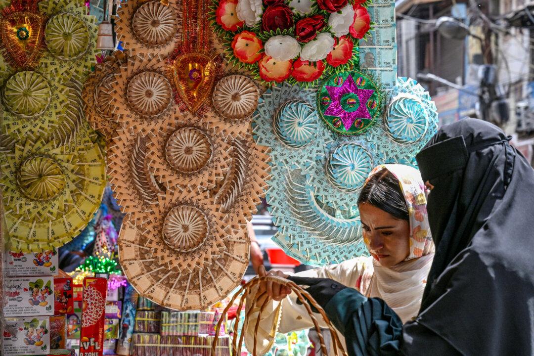 Women shop at a market as garlands made of Indian currency notes are displayed for sale in Srinagar on May 15, 2026. (Photo by Tauseef MUSTAFA / AFP via Getty Images)