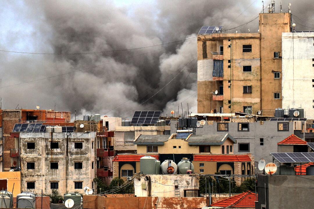 TOPSHOT - Smoke rises behind buildings following an Israeli airstrike in the southern city of Tyre on May 15, 2026. Israel carried out new strikes in southern Lebanon that it said targeted the militant group Hezbollah on May 15, hours before the two countries' envoys were set to meet for a second day of peace talks in Washington. (Photo by KAWANT HAJU / AFP via Getty Images)