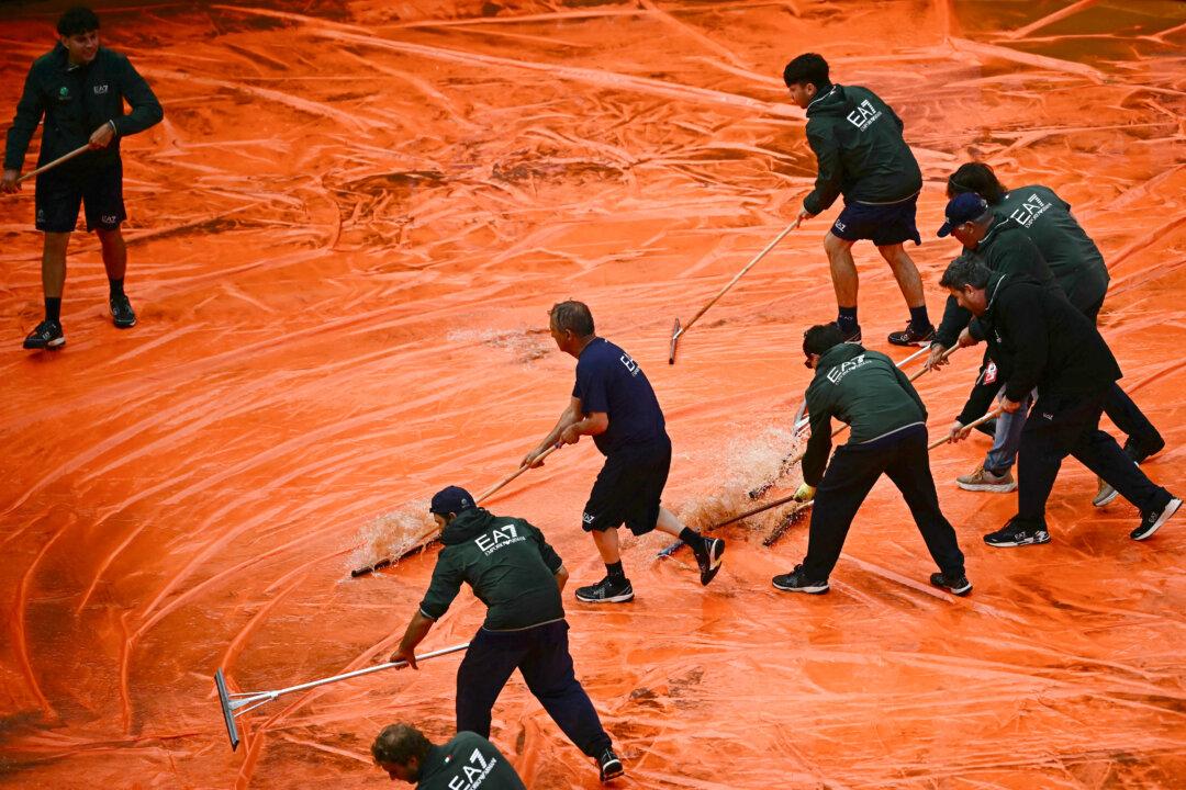 TOPSHOT - Staff remove water from the tarp covering the clay court after the semi-final match between Italy's Luciano Darderi and Norway's Casper Ruud was interrupted due to a storm during the ATP Rome Open tennis tournament at Foro Italico in Rome on May 15, 2026. (Photo by Filippo MONTEFORTE / AFP via Getty Images)