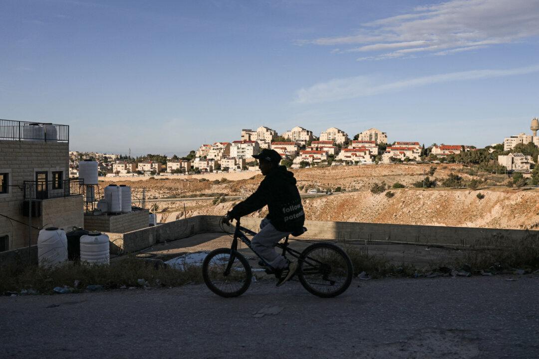 A man cycles along a road in the Palestinian town of al-Eizariya overlooking the Israeli settlement of Maale Adumim (background), on the outskirts of Jerusalem in the Israeli-occupied West Bank, on May 15, 2026. Excluding east Jerusalem, more than 500,000 Israelis live in the occupied West Bank in settlements that are illegal under international law, among some three million Palestinians. (Photo by AHMAD GHARABLI / AFP via Getty Images)