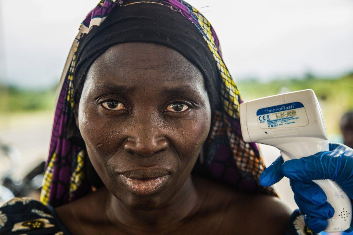 Medical staff check the temperature of a woman who arrived in Uganda, from Congo through the Busunga border, at a screening facility in Bundibugyo district, western Uganda, on Aug. 17, 2018. (Sumy Sadurni /AFP via Getty Images)