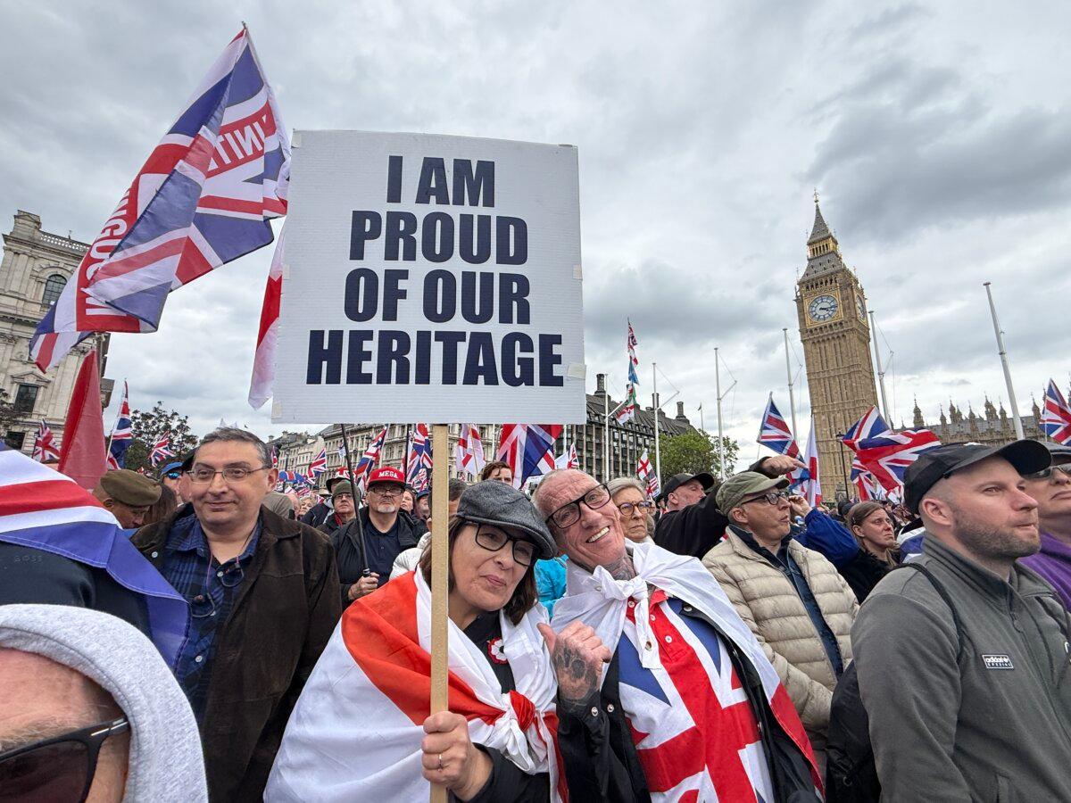 A couple attends Tommy Robinson’s “Unite the Kingdom” rally in London on May 16, 2026. (Wen Qing/The Epoch Times)