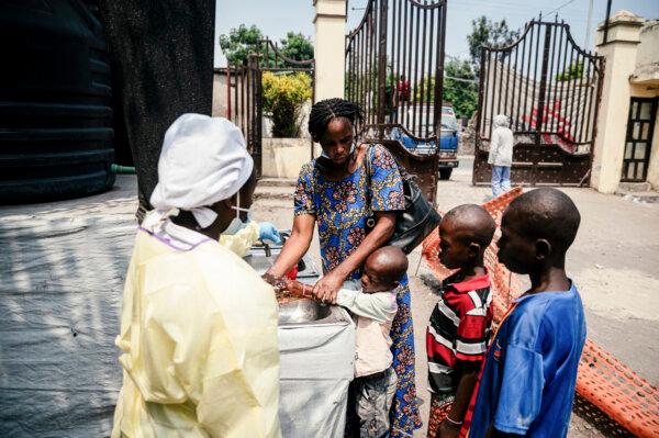 A mother helps her children wash their hands before entering Kyeshero Hospital in Goma on May 18, 2026. (Jospin Mwisha / AFP via Getty Images)