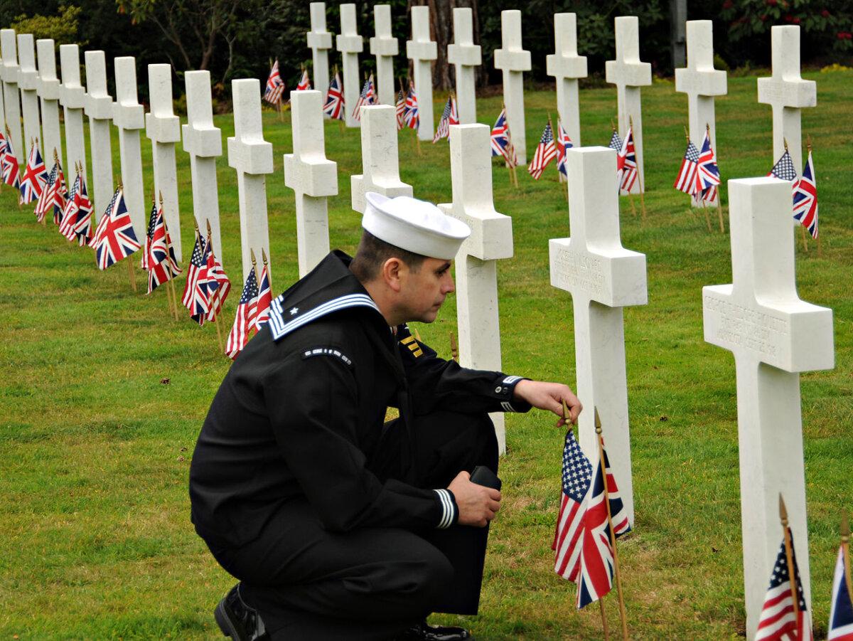Petty Officer 1st Class Samuel Hernandez-Moreno, ship's serviceman, assigned to the aircraft carrier USS George H.W. Bush, pays his respects to a fallen service member buried at the Brookwood American Cemetery and Memorial on Memorial Day, 2011. (Dvidshub/CC BY-SA 2.0)