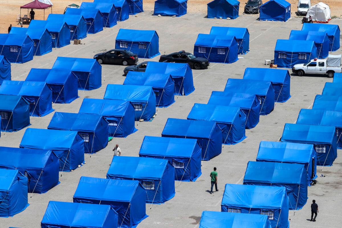 Displaced Lebanese people walk between blue tents set up by the government for people who fled their homes and villages in Beirut's southern suburbs and southern Lebanon, replacing informal tent settlements on the capital's seafront on May 22, 2026. (Anwar Amro/AFP via Getty Images)