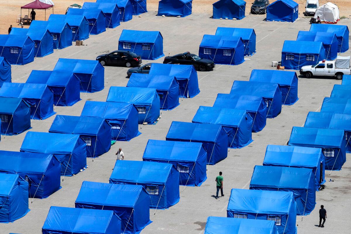 Displaced Lebanese walk between blue government-set-up tents for people who fled their homes and villages in Beirut's southern suburbs and southern Lebanon, replacing informal tent settlements on the capital's seafront, on May 22, 2026. (Anwar Amro/AFP via Getty Images)