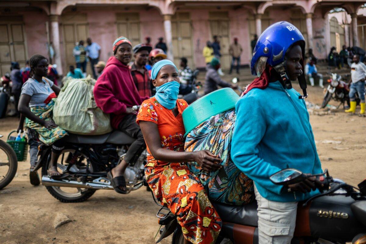 Motorcycle taxi riders and their passengers wait at the entrance to the central market while sanitation workers disinfect the area, as Ituri Province continues to combat an Ebola outbreak in Bunia, Congo, on May 23, 2026. (Moses Sawasawa/AP)