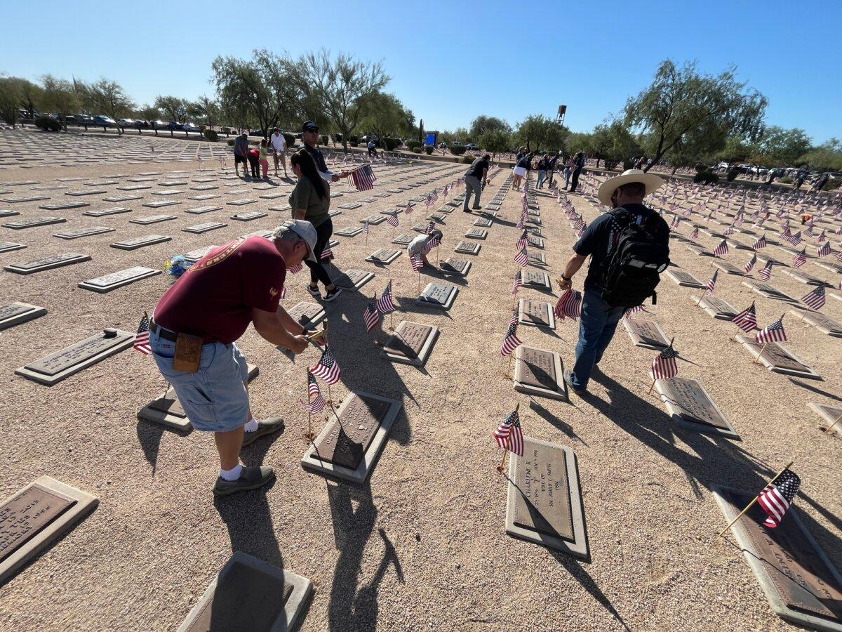 Volunteers insert flags at the National Memorial Cemetery of Arizona in Phoenix on May 23, 2026. (Allan Stein/The Epoch Times)