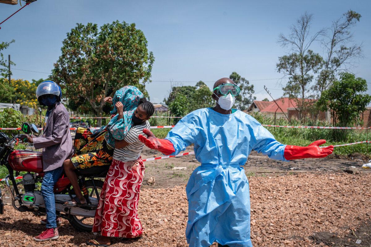 Dieudonné Sezabo (R), a health worker, gestures as he asks for help in transporting a patient (2nd L) suspected of having Ebola, who was brought by motorcycle taxi to the Rwampara Hospital in Ituri, Congo, on May 26, 2026. (Glody Murhabazi/AFP via Getty Images)