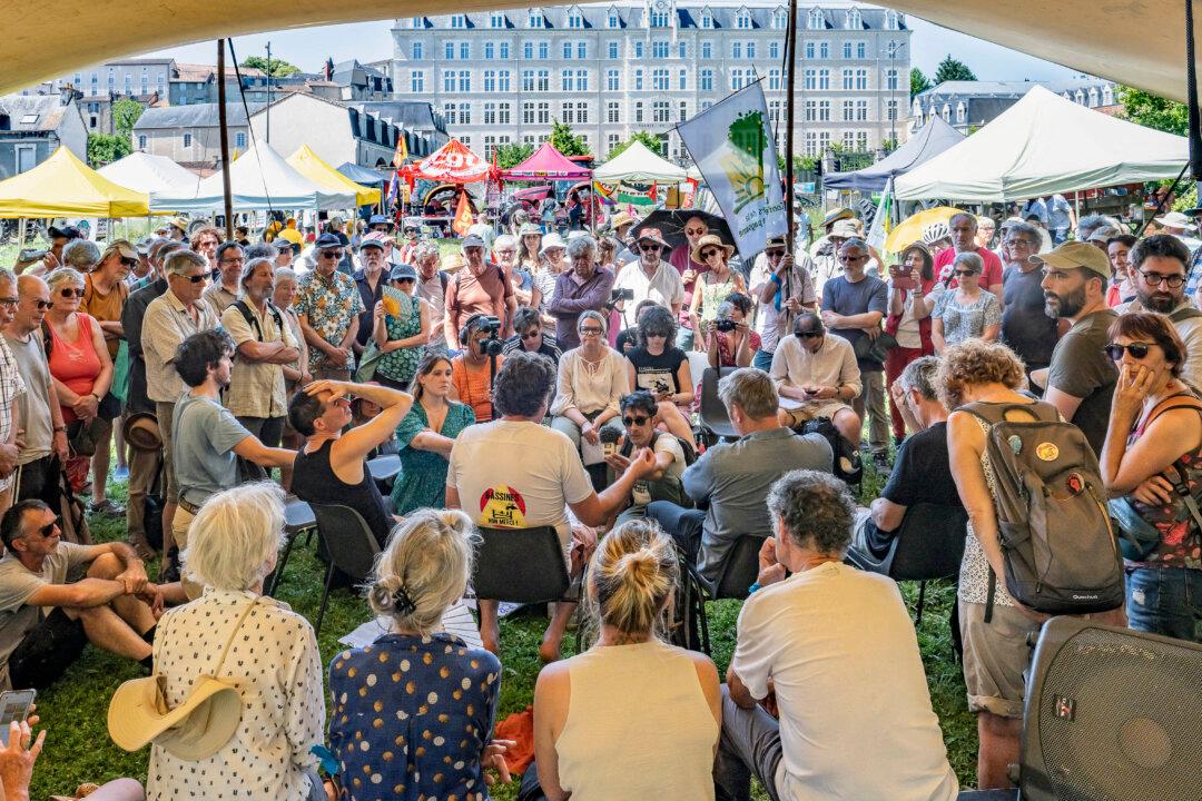 A crowd of people surrounds Julien Le Guet, seen here from behind in the centre of the image wearing a T-shirt bearing the 'Bassines Non Merci' logo; he is due to stand trial again on appeal in a few moments' time at the court in Poitiers, on 27 May 2026. He is accused of organising the anti-mega-basin protest in Sainte Soline in March 2023. Three other environmental activists and trade union leaders are also on trial on the same day. (Photo by Jean-François FORT / Hans Lucas / AFP via Getty Images)