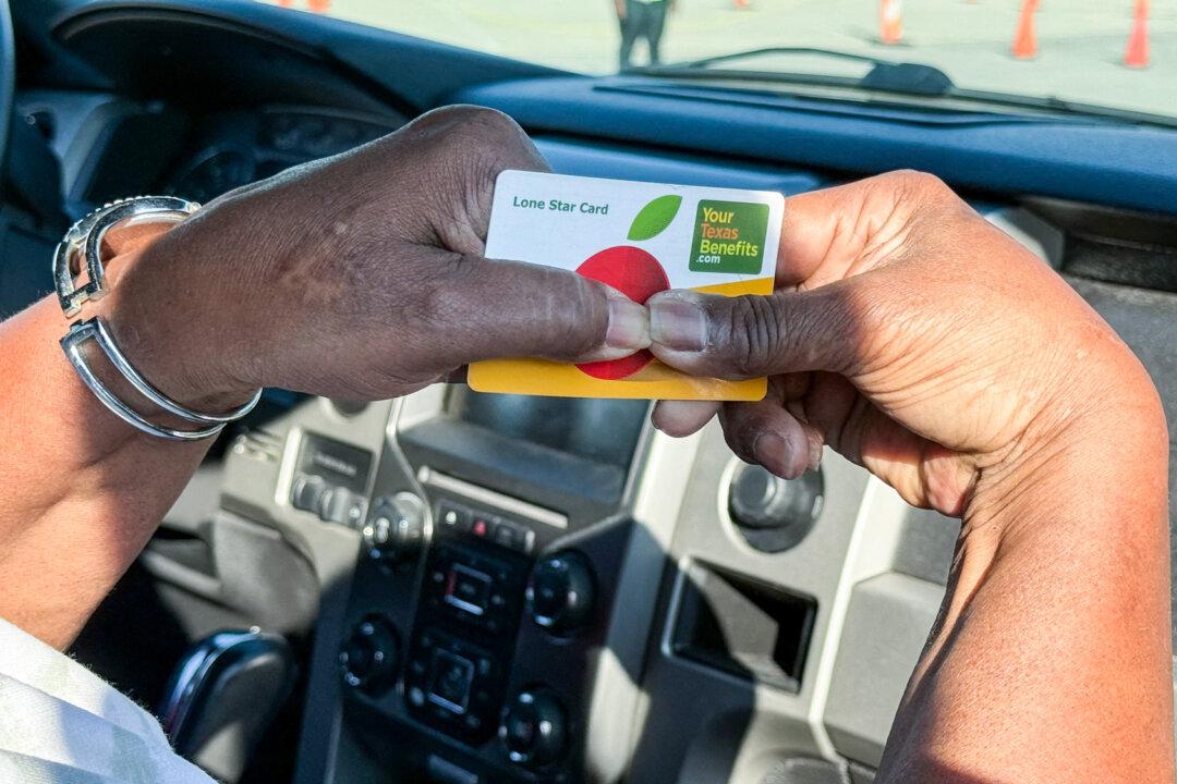 A Houston resident holds a card identifying her as a SNAP beneficiary while she waits to get supplies from the Houston Food Bank Program at NRG Stadium in Houston on Nov 1, 2025. About 39 million people receive food stamps benefits each month, according to the USDA. (Moisés Ávila/AFP via Getty Images)