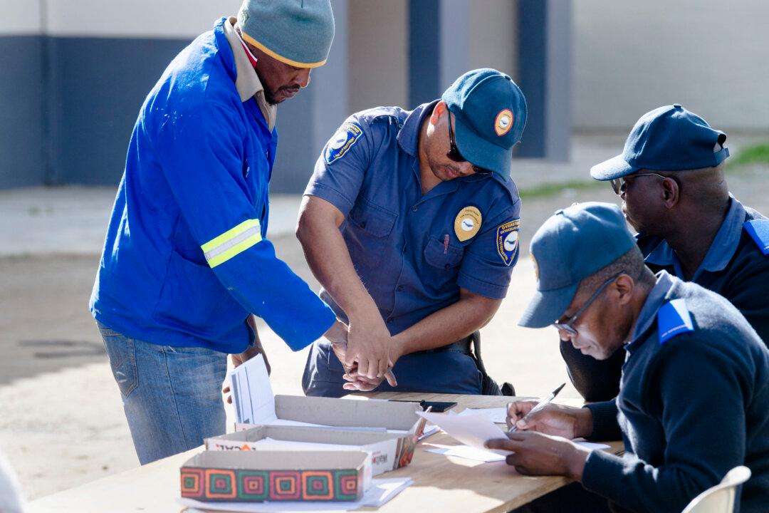 Provincial Law Enforcement officers (R) take a man's fingerprints as they document migrants, in Stanford about 140km from Cape Town, on June 05, 2026. A 19-year-old South African was stabbed to death on the night the two Mozambicans were killed, but police are reluctant to link his death to the anti-migrant tensions. Nearly 600 Mozambicans fled Mossel Bay and returned home in the days following the violence, according to the border management authority.
Nearly a week later, around 100 foreign nationals from Malawi, Mozambique and Zimbabwe were still crammed into a Mossel Bay community hall with their belongings, guarded by police.
With them were several South Africans from another province, Limpopo, who feared they could also be targets because they are not Xhosa. (Photo by RODGER BOSCH / AFP via Getty Images)