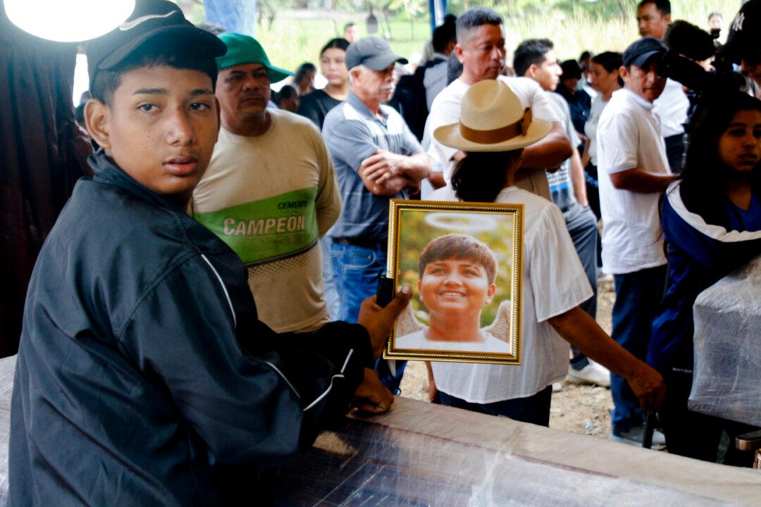 A youngster mours during the funeral of eight people who had gone missing and were found killed, in Daule, Guayas, Ecuador, on June 5, 2026. Ecuadoran police said on June 3, 2026 they found eight bodies in plastic bags in a southwestern narco-trafficking hotspot, where eight people had gone missing. (Photo by Gerardo MENOSCAL / AFP via Getty Images)
