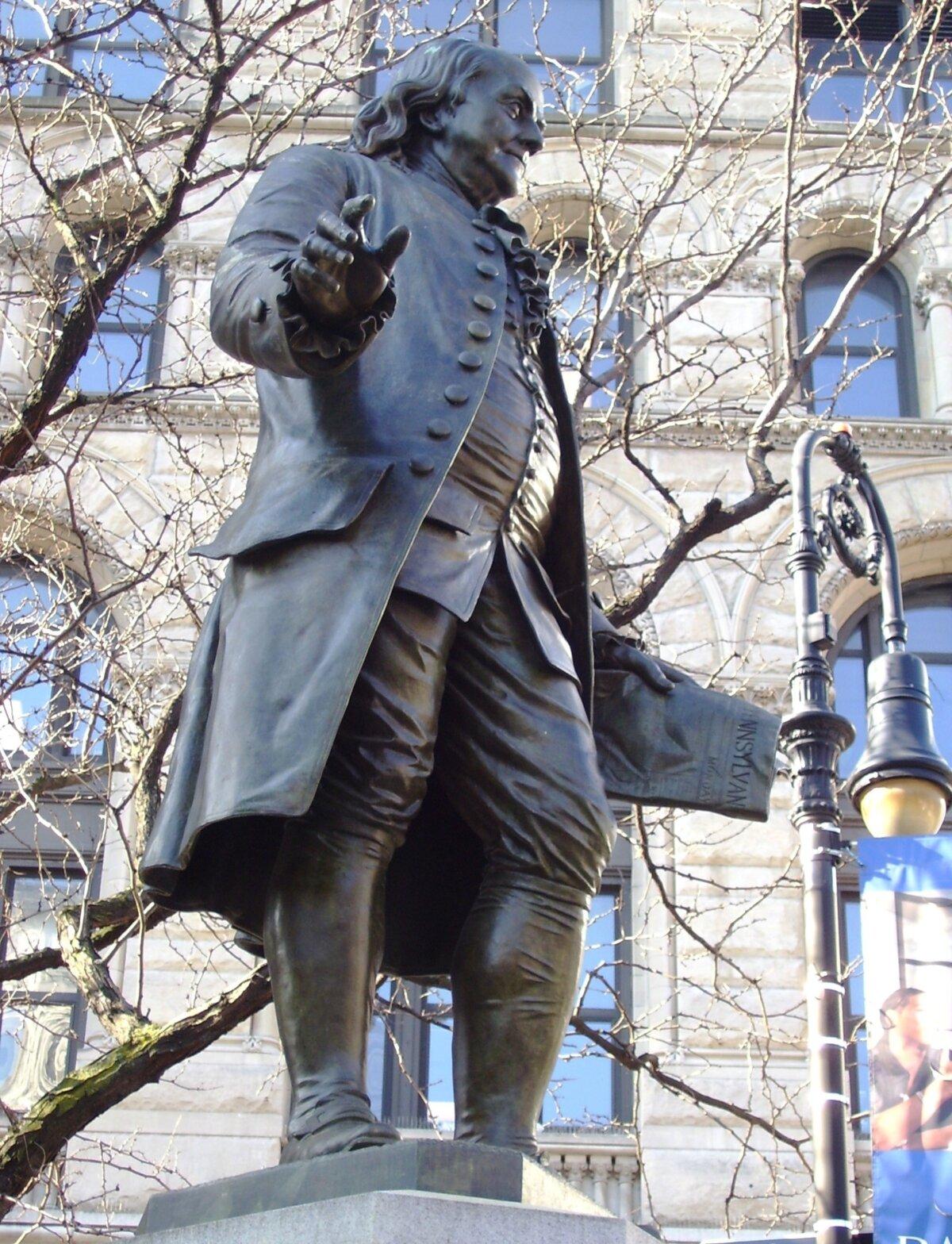 A statue of Benjamin Franklin in the Financial District of Manhattan, New York City; the plaza was once known as "Printing House Square" due to the offices and presses of numerous newspapers which were situated in the area. Franklin is holding a copy of his Pennsylvania Gazette. (<a href="https://commons.wikimedia.org/wiki/User:Beyond_My_Ken">Beyond My Ken</a>/<a href="https://creativecommons.org/licenses/by-sa/4.0">CC BY-SA 4.0</a>)