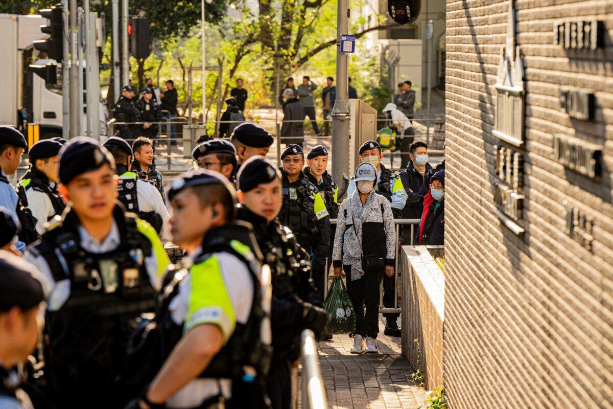 Police keep watch as people enter the West Kowloon Law Courts building to hear the verdicts in the national security trial of pro-democracy media tycoon Jimmy Lai in Hong Kong on Dec. 15, 2025. (Leung Man Hei / AFP)