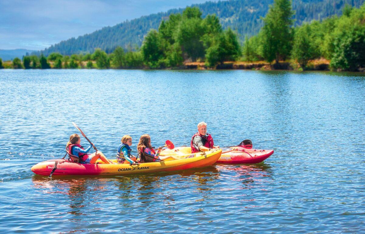 Ranch owner Britton guides a kayak for three young children. (Maria Coulson)