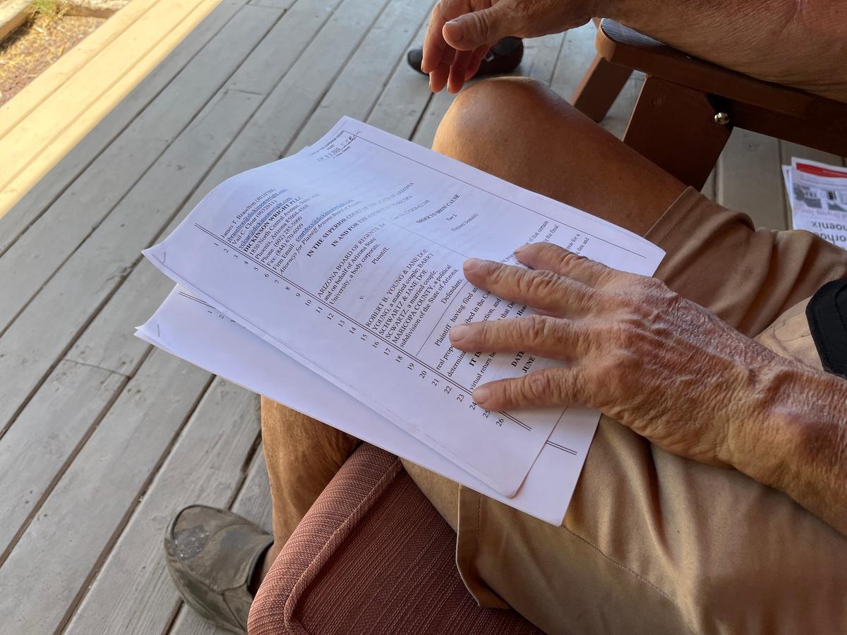 Robert Young reads a copy of the condemnation complaint from Arizona State University seeking to take his property by eminent domain, in Phoenix on June 13, 2026. (Allan Stein/The Epoch Times)