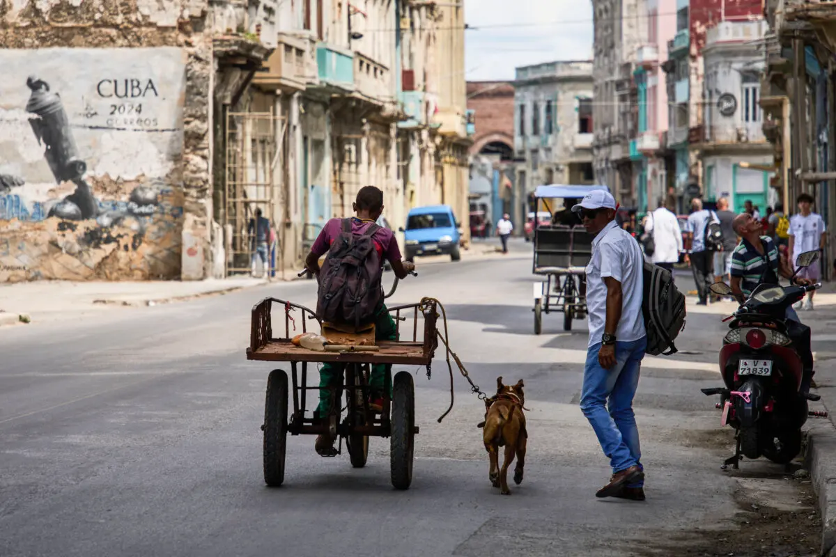 A man rides a tricycle with his leashed dog running alongside him during a blackout in Havana, Cuba, on March 16, 2026. (Ramon Espinosa/AP)