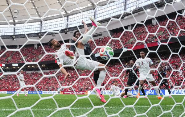 Canada's Jonathan David (back) scores past Qatar's Boualem Khoukhi during the first half of a World Cup Group B soccer match, in Vancouver on June 18, 2026. (The Canadian Press/Darryl Dyck)