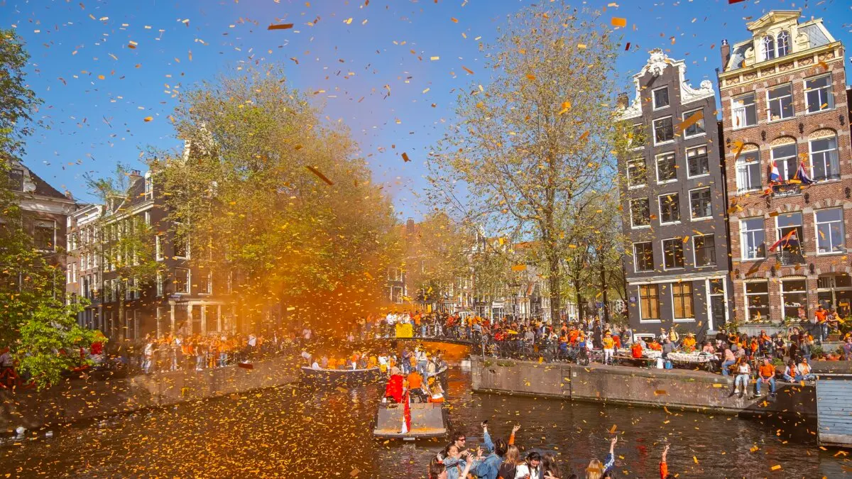 Crowds celebrate King’s Day with orange smoke and confetti on the canals of Amsterdam in the Netherlands on April 27, 2026. (Shutterstock/Steve Photography)