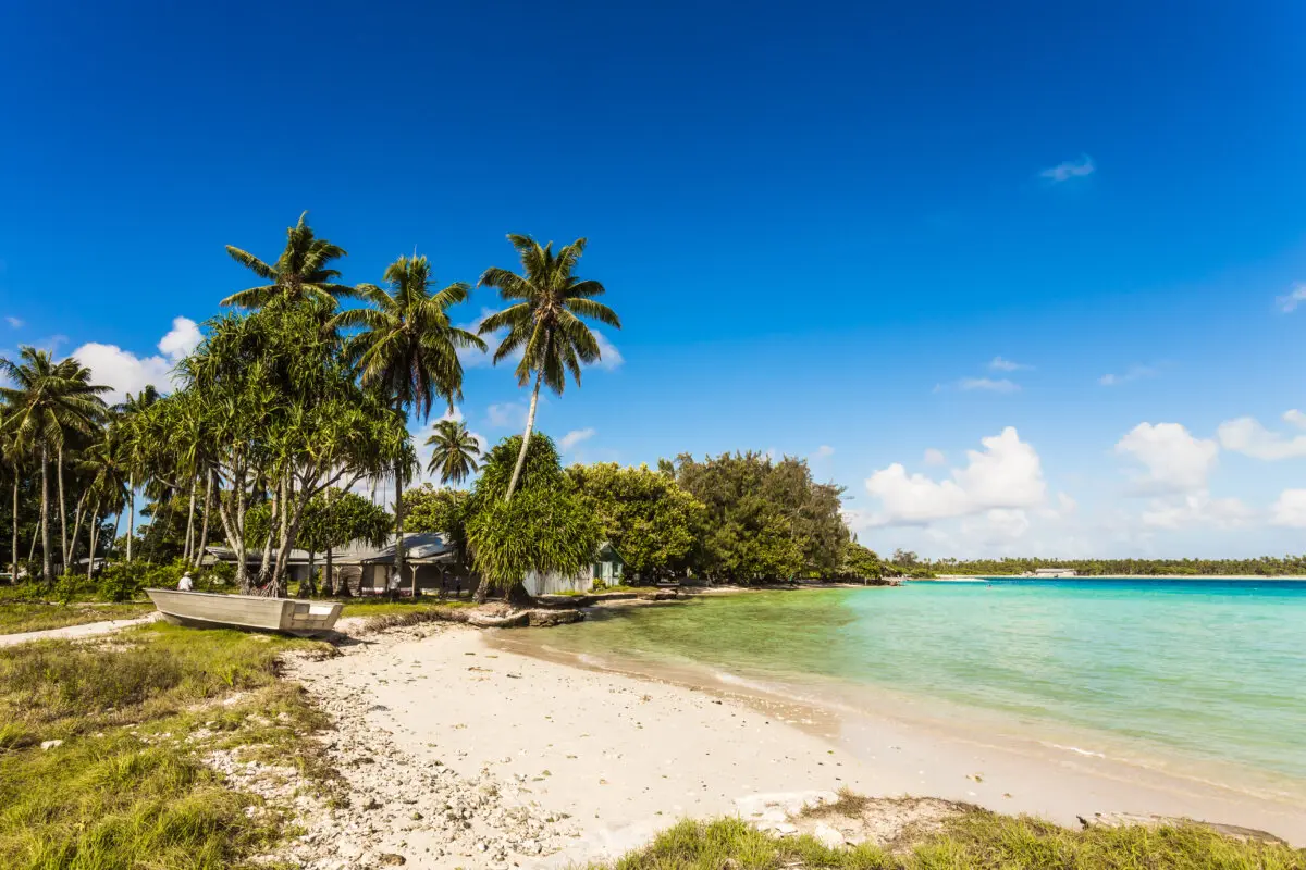 Sandy beach with coconut trees and huts on the island of Kiribati. (Shutterstock/Vyshnivskyy)