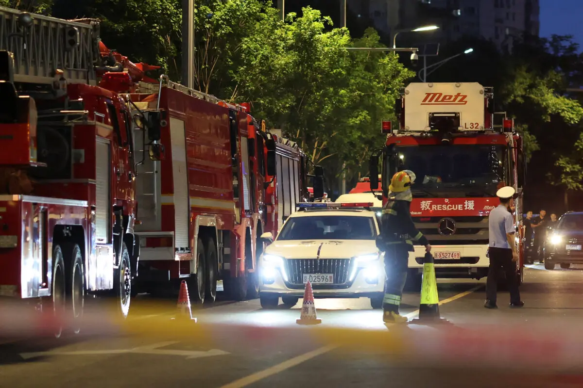 Rescue workers stand near firetrucks behind a cordon line on a road next to CITIC Tower in Beijing on June 26, 2026. (Maxim Shemetov/Reuters)