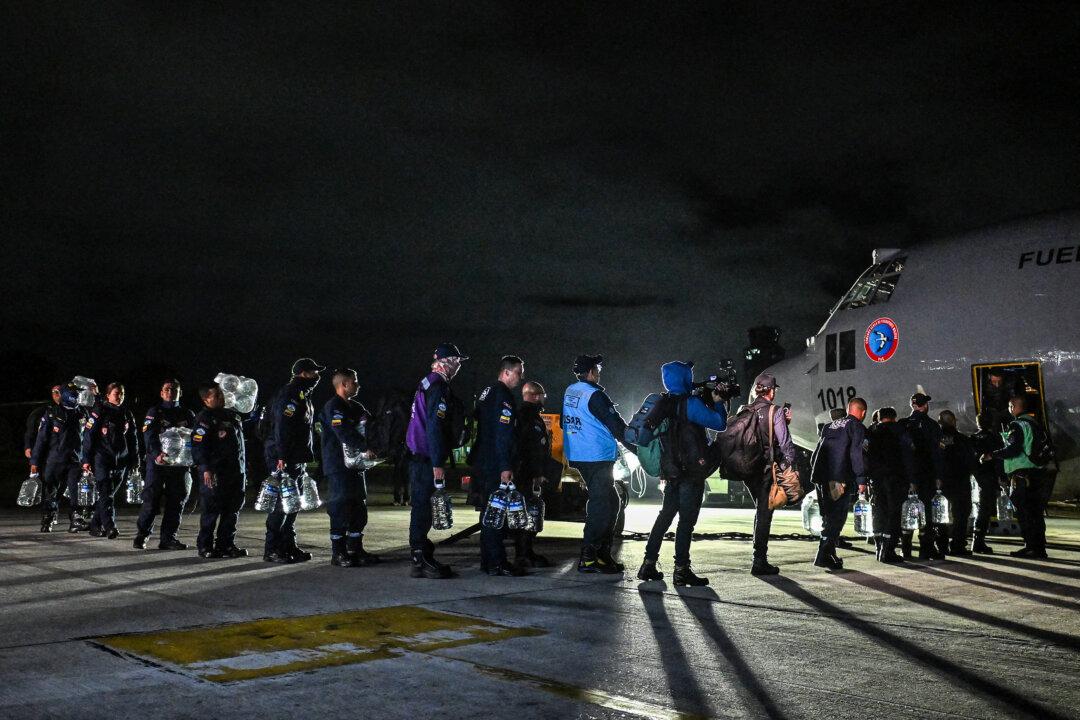 Colombian firefighters carrying bottles of water board a Colombian Air Force plane with humanitarian aid to Venezuela at Catam Air Base in Bogota on June 26, 2026, following deadly earthquakes. Desperate Venezuelans raced to find and rescue loved ones trapped alive beneath the rubble of collapsed buildings after two major earthquakes, measured at magnitudes 7.2 and 7.5, hit northern Venezuela killing -up to now- 589 people and leaving more than 1,500 injured. (Photo by Luis ACOSTA / AFP via Getty Images)
