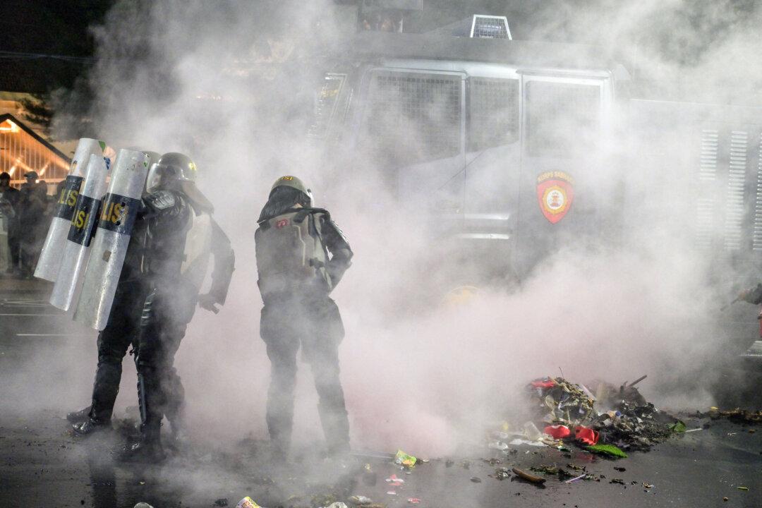 Riot police put out a fire during following clashes during protest against a rise in non-subsidised fuel prices, inefficient government spending and military involvement in civilian affairs and the government's free school meals programme (MBG) in Surabaya on June 26, 2026. (Photo by Juni KRISWANTO / AFP via Getty Images)