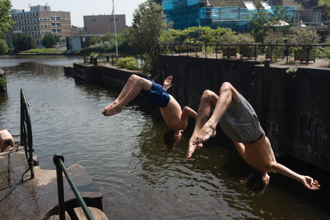 Two boys do a backflip into a canal in The Hague on June 26, 2026. The KNMI Dutch weather service for the first time issued a code red for extreme heat in all provinces. (Photo by Lina SELG / AFP via Getty Images)