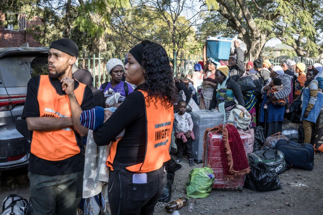 TOPSHOT - A South African Immigration Officers holds a Malawian infant born from an undocumented migrants mother as women gather hoping to board buses taking them back home at a temporary site along Mayor's Walk in Pietermaritzburg, on June 26, 2026. South Africans President Cyril Ramaphosa vowed on Thursday to crush any attempts to destabilise the nation during planned anti-immigrant marches next week, amid a wave of xenophobia.Citizen-led groups have set Tuesday 30 as a deadline for undocumented foreigners to leave and called for nationwide marches against illegal immigration, marking a crescendo in months of protests that have at times turned violent. (Photo by MARCO LONGARI / AFP via Getty Images)