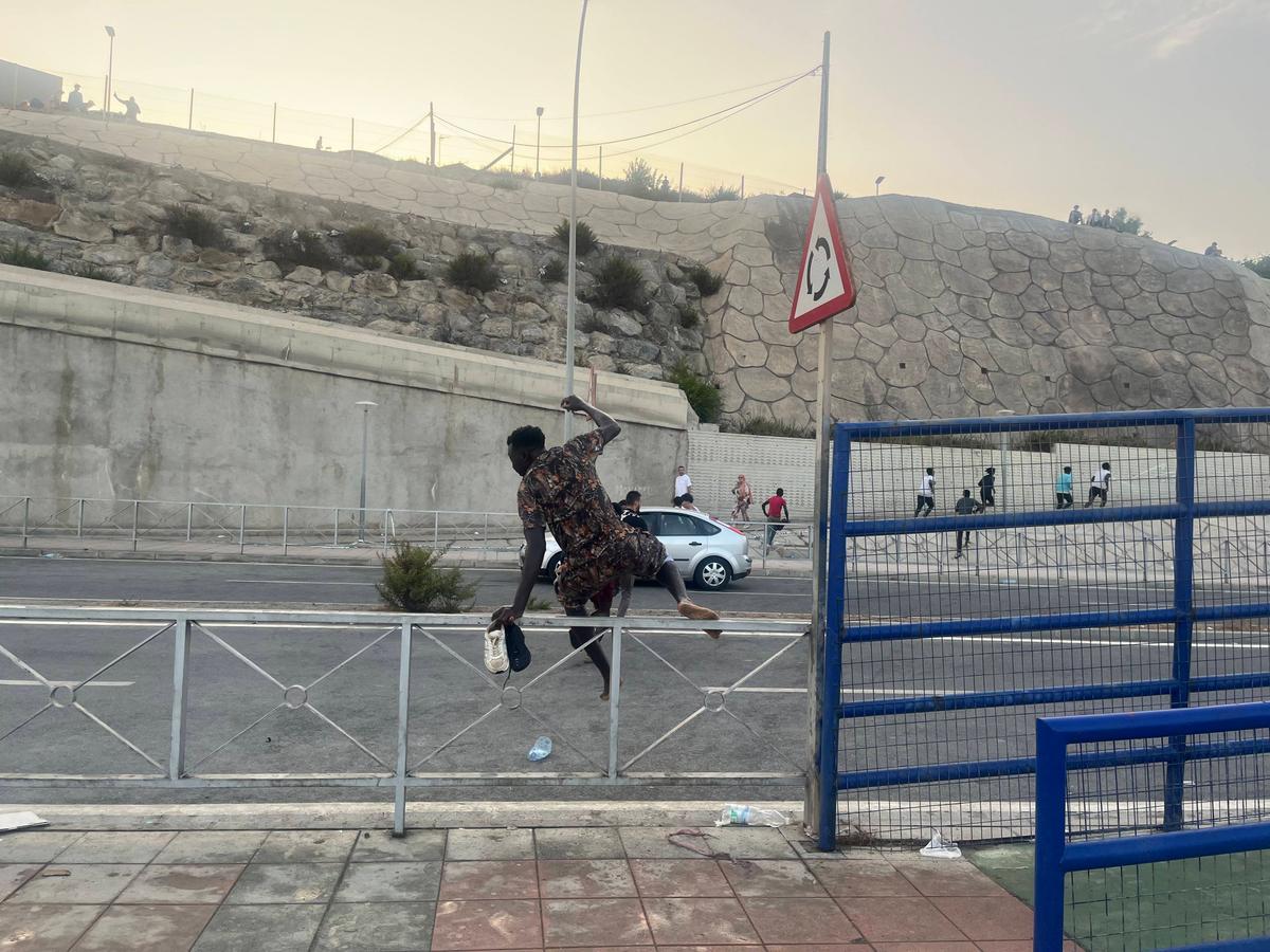 An African migrant climbs over a roadside barrier while running toward the city of Ceuta on July 31, 2026. (Etienne Fauchaire/The Epoch Times)