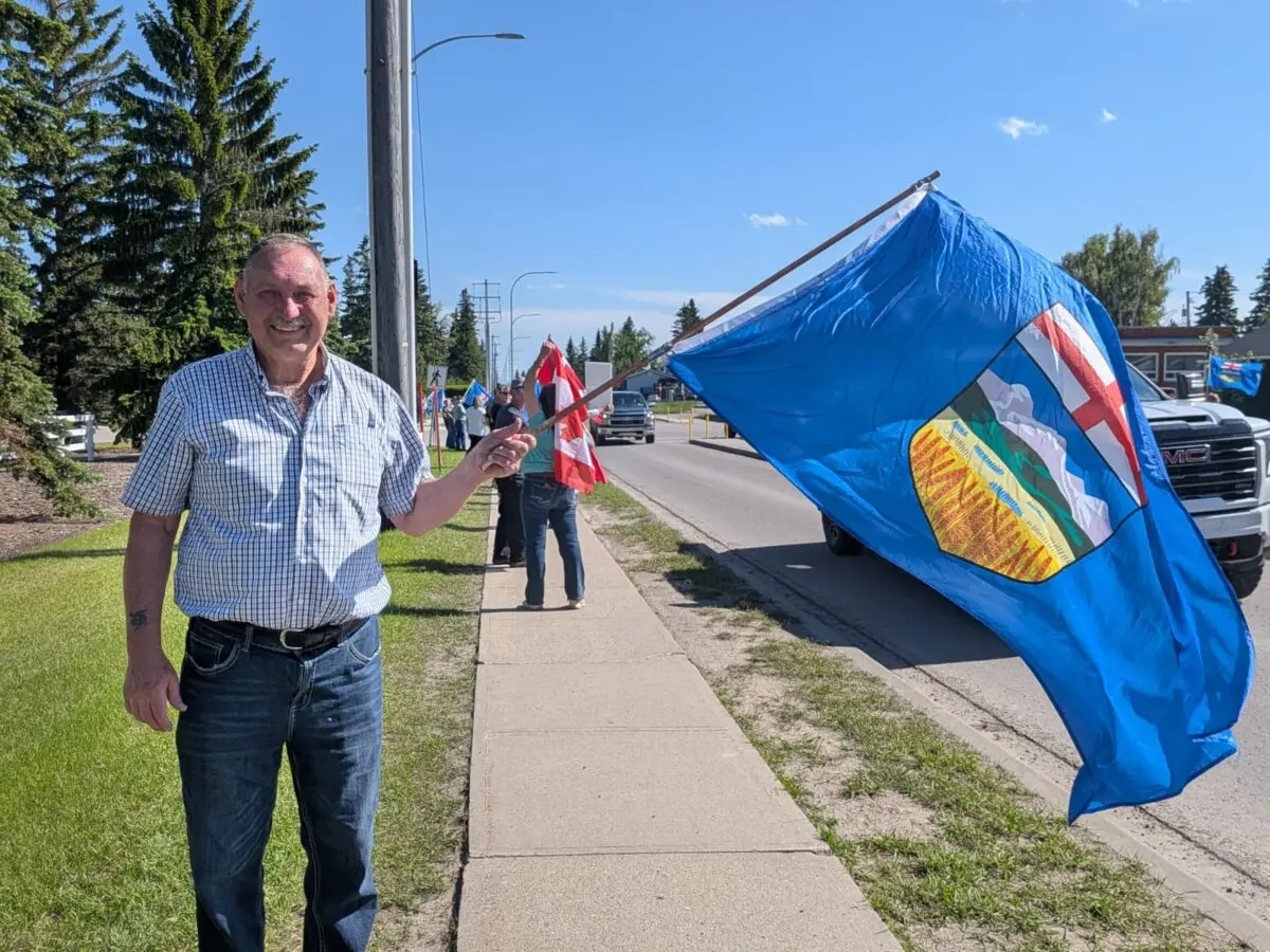 Alberta independence supporter Randy Ackert waves an Alberta flag ahead of a UCP event with Alberta Premier Danielle Smith in Olds, Alta., on June 24, 2026. (Paul Rowan Brian/The Epoch Times)