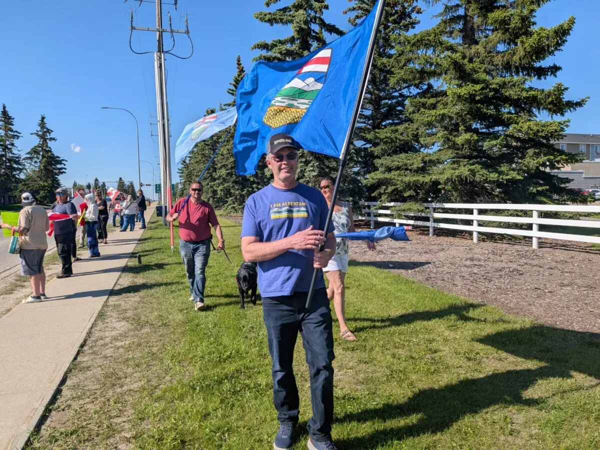 Alberta independence supporter Dennis Dueck waves an Alberta flag ahead of an event with Alberta Premier Danielle Smith in Olds, Alta., on June 24, 2026. (Paul Rowan Brian/The Epoch Times)