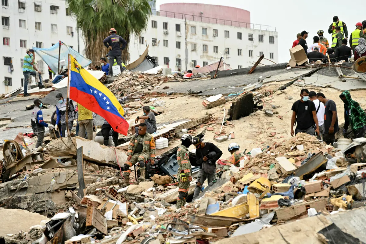 Rescuers and volunteers work amid the rubble of collapsed buildings, as a Venezuelan flag is raised, in Caraballeda, La Guaira state, Venezuela, on July 3, 2026. (Martin Beretti / AFP via Getty Images)