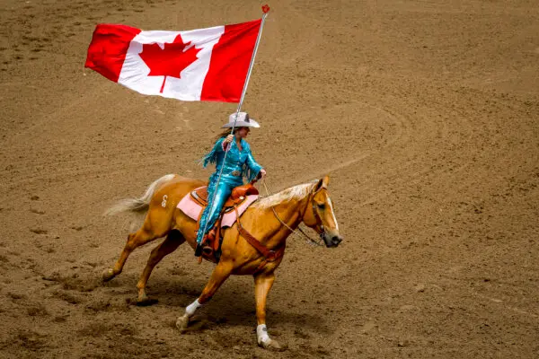 Calgary Stampede Princess Sarah O'Brien carries the Canadian flag during the national anthem before the start of rodeo action at the Calgary Stampede in Calgary, Alta., on July 3, 2026. (The Canadian Press/Jeff McIntosh)