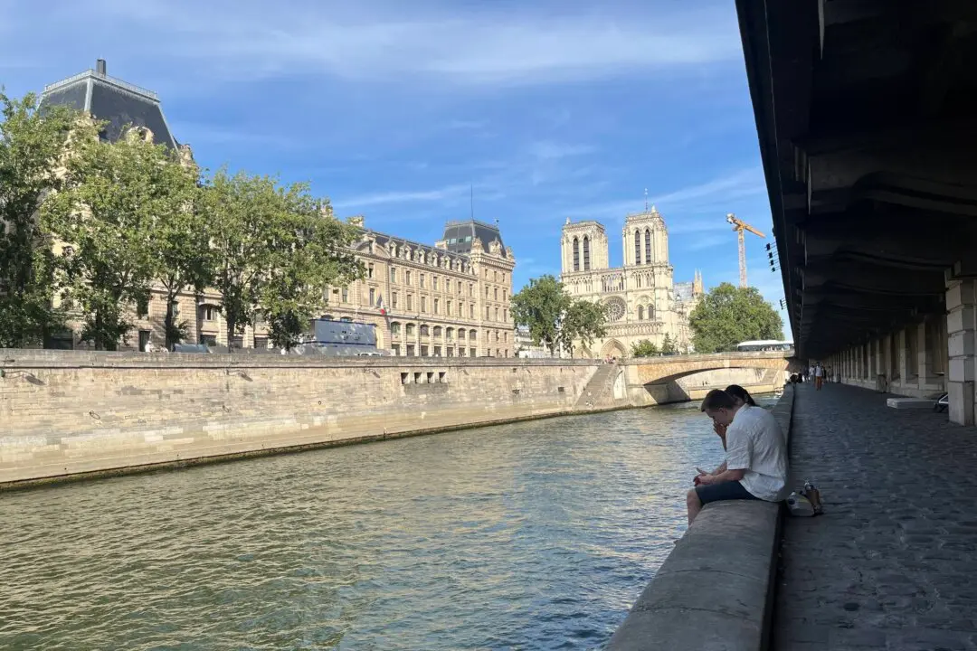 Parisians relax in the shade along the banks of the Seine to escape the heat on July 5, 2026. (Etienne Fauchaire/The Epoch Times)