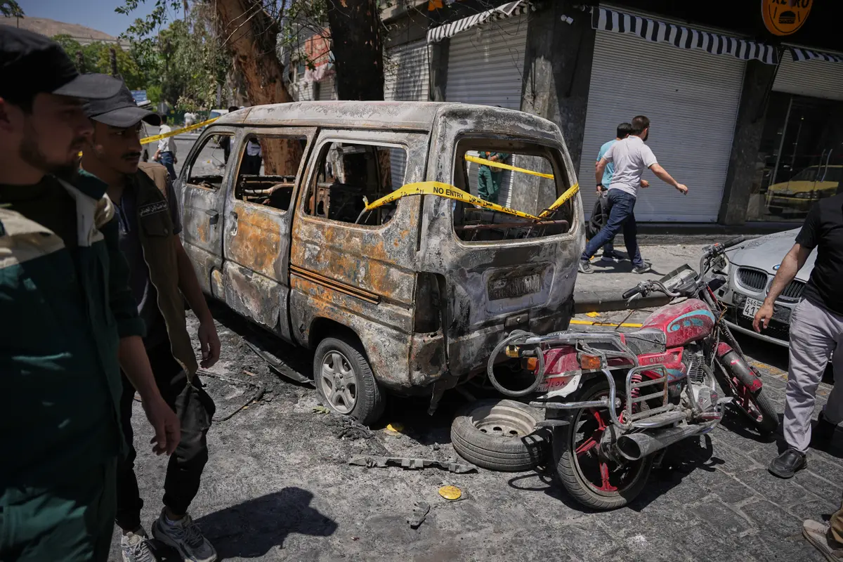 Syrian security personnel inspect a burned vehicle near the Four Seasons Hotel after two explosions rocked the area earlier while Syrian President Ahmad al-Sharaa was meeting French President Emmanuel Macron at the presidential palace, in Damascus, Syria, on July 7, 2026. (Omar Albam/AP Photo)