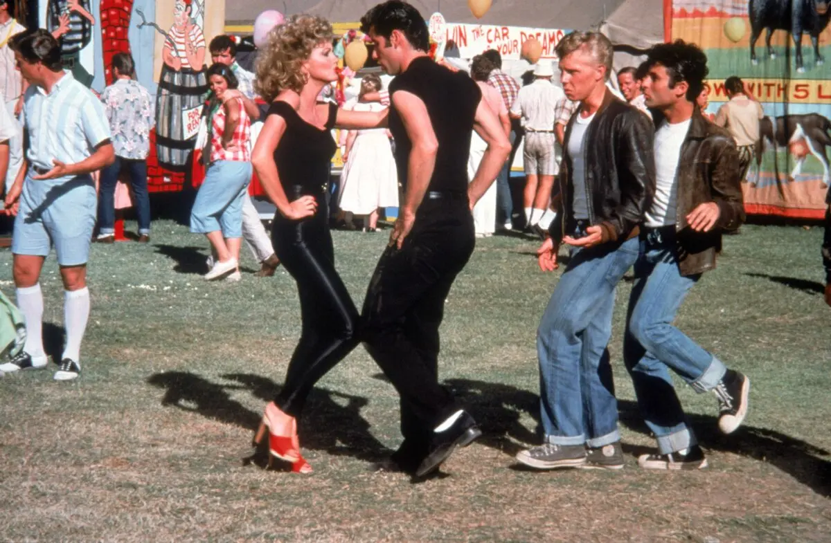 (L–R) Sandy Olsson (Olivia Newton-John), Danny Zuko (John Travolta), Putzie (Kelly Ward), and Sonny (Michael Tucci), in “Grease.” (Paramount Pictures/MovieStillsDB)