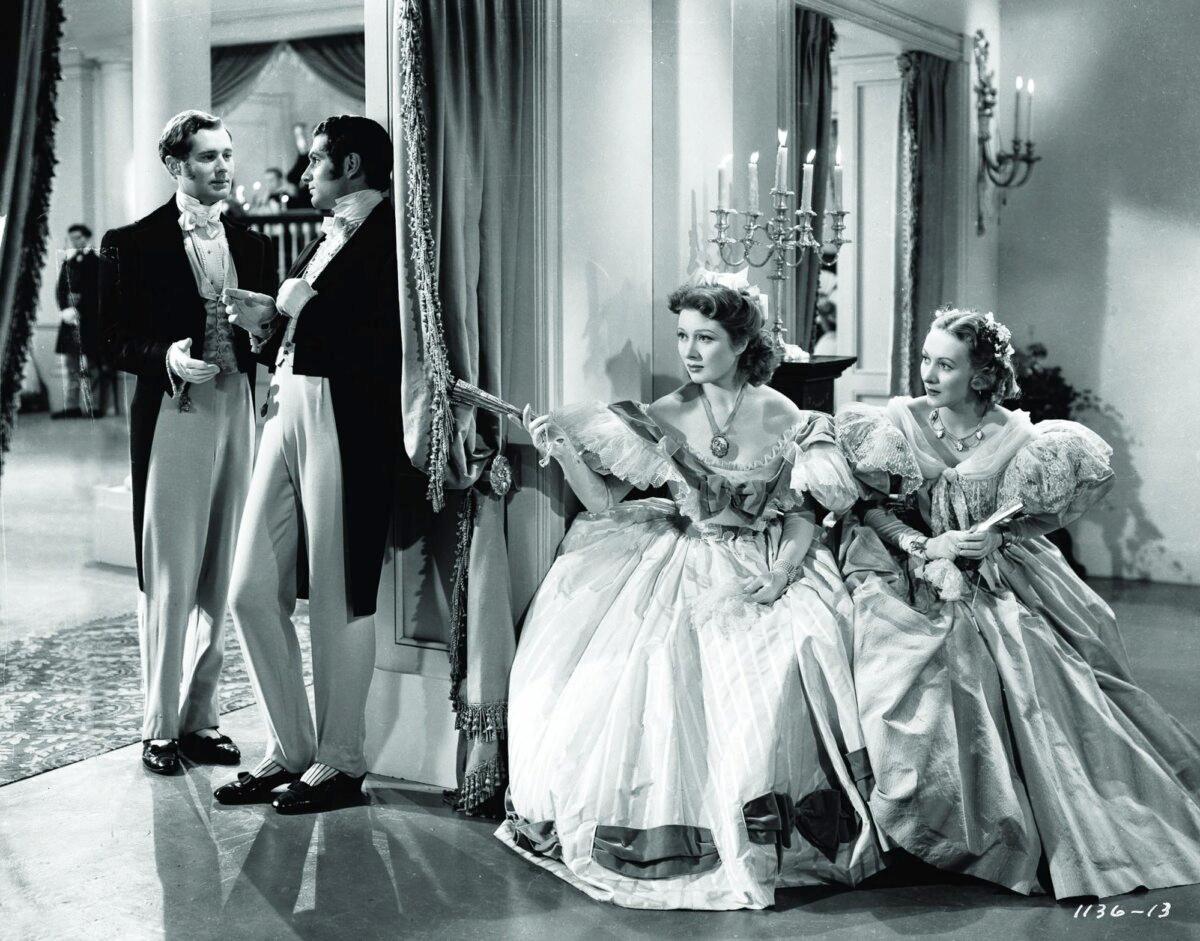 (L–R) Darcy (Laurence Olivier) and Bingley (Bruce Lester) talk while Elizabeth Bennet (Greer Garson) and (Karen Morley) listen, in “Pride and Prejudice.” (MGM)