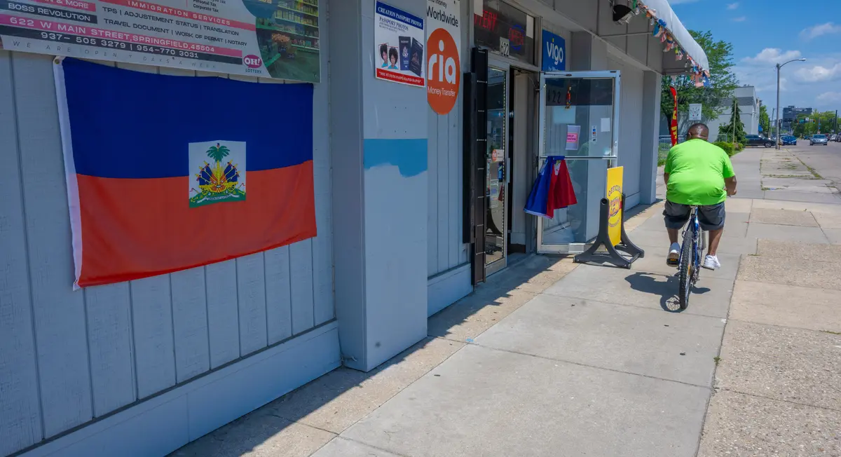 A bicyclist rides past the Haitian flag on the wall of Creation Market in West Main Street in Springfield, Ohio, on July 3, 2026. (Glenn Hartong for The Epoch Times)