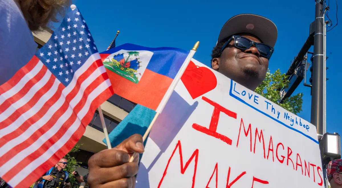 Haitian protected status holder Biassu Pierre from Haiti has been in Springfield, Ohio, for three years. Here, with Haitian and American flags in his hand, he attends a pro-Haitian demonstration at the Springfield City Hall, in Springfield, Ohio, on July 3, 2026. (Glenn Hartong for The Epoch Times)
