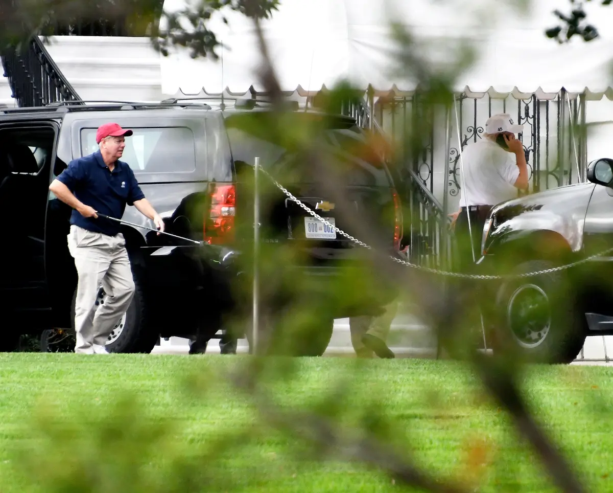 Senator Lindsey Graham (R-S.C.), left, carries one of his golf clubs as he leaves the presidential limo at the White House on Oct. 14, 2017. (Ron Sachs - Pool/Getty Images)