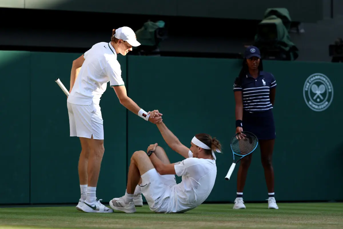 Alexander Zverev of Germany is helped back up by Jannik Sinner of Italy after falling during their Gentlemen's Singles final match on day 14 of The Championships Wimbledon 2026 at All England Lawn Tennis and Croquet Club in London on July 12, 2026. (Clive Brunskill/Getty Images)