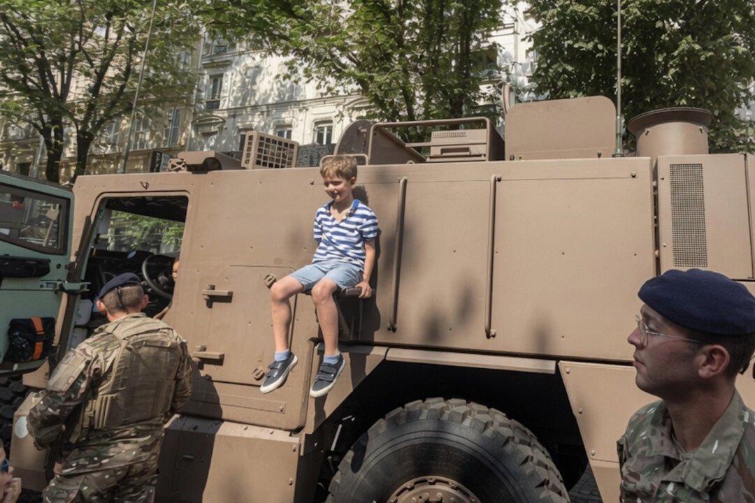 A young French man waits for his turn to climb aboard an army truck during France's National Day celebrations on July 14. (Etienne Fauchaire/ The Epoch Times)