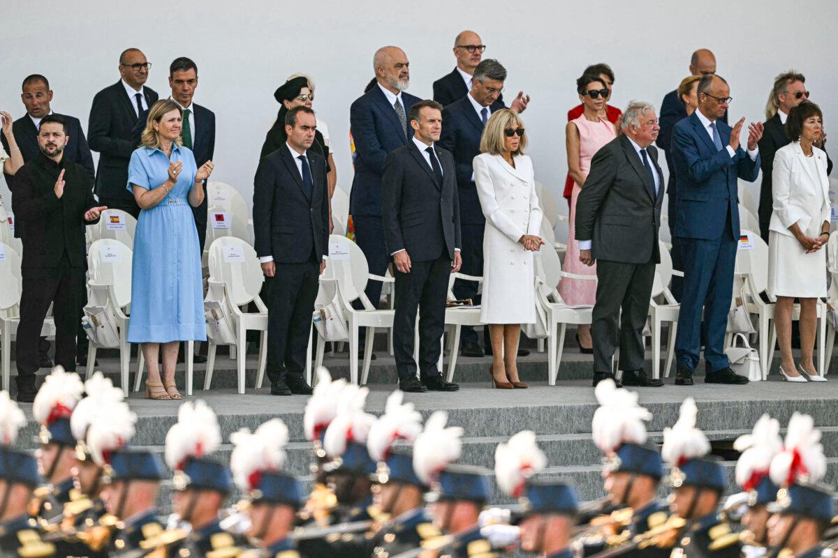 (From L, first row) Ukrainian President Volodymyr Zelensky; President of the French National Assembly Yael Braun-Pivet; French Prime Minister Sebastien Lecornu; French President Emmanuel Macron and his wife, Brigitte Macron; President of the French Senate Gerard Larcher; and German Chancellor Friedrich Merz attend the annual Bastille Day military parade at the Place de la Concorde in Paris, on July 14, 2026. (Photo by Lou Benoist / AFP via Getty Images)