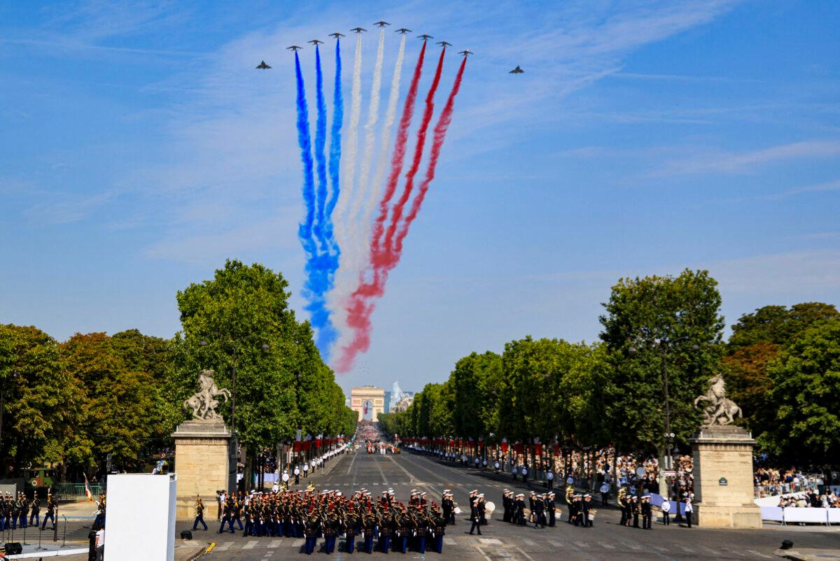 France's Air Force Elite aerobatic flying team “Patrouille de France” releases trails of France's national colours as they perform a flyover during the annual Bastille Day military parade on the Champs-Élysées Avenue with the Arc de Triomphe in the background, in Paris on July 14, 2026. (Ludovic Marin / AFP via Getty Images)