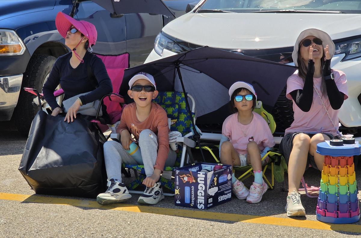 A family from Regina watches in wonder and amazement as the Snowbirds perform rolls and loops during their annual Hometown Event in Moose Jaw, Sask., on July 11, 2026. (Jason G. Antonio for The Epoch Times)