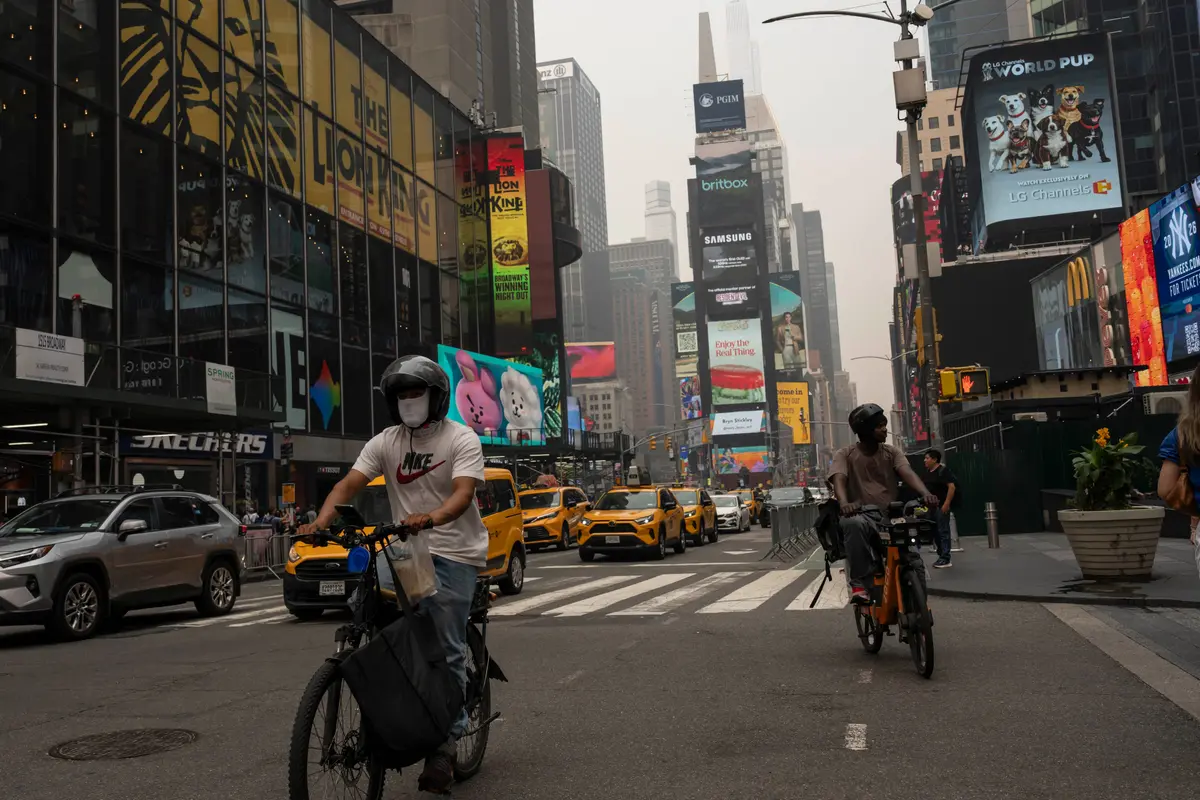 A person wearing a mask cycles in Times Square amid smoky skies in New York on July 16, 2026. (Yuki Iwamura/AP Photo)